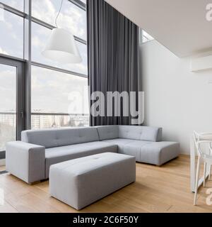 Contemporary living room with gray corner sofa and big window wall Stock Photo