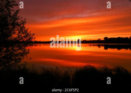Symmetry of the sky in a lake at sunrise. Clouds reflecting on the water. Holiday landscape by the sea. Quiet relaxing scene with a beautiful colorful