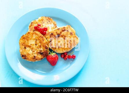 Healthy breakfast concept. Close up cottage cheese pancakes with fresh blueberries and on blue background. Stock Photo