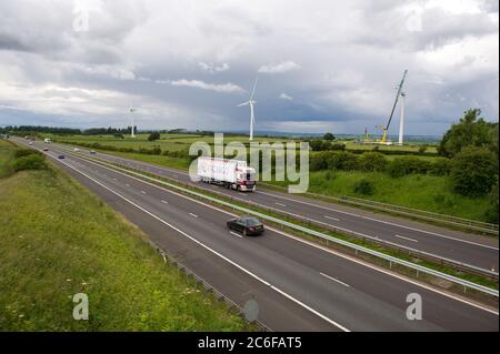 Larkhall, Scotland, UK. 9th July, 2020. Pictured: A huge wind turbine stands a few hundred feet tall whilst its blades lay on the ground ready to be attached. Green energy is is big business, and if the UK is to archive its targets for renewable energy then more wind turbines onshore and offshore need to be built. Credit: Colin Fisher/Alamy Live News