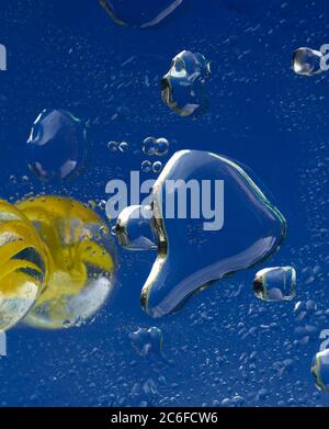 Blue accent colour, single glass marble and water droplets on blue, Stock Photo