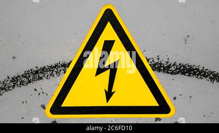 dirty yellow high voltage warning sign isolated on gray background Stock Photo