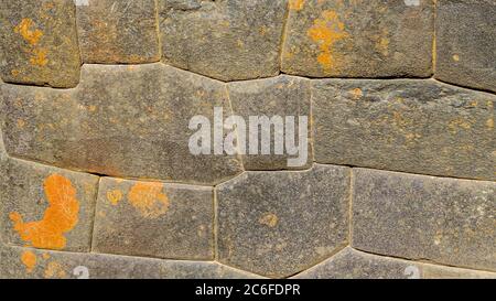 inca stone wall with perfect shaped granite and fitting stones, orange fields covered gray peruvian stones from ancient architecture pattern Stock Photo