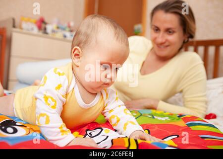 Close up of caring beautiful young mother teaches colors her six-month-old charming daughter lying in a cozy childrens room. The concept of care and p Stock Photo