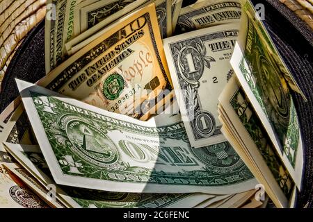 straw hat with a stack of dollar bills inside, donated to a successful beggar Stock Photo