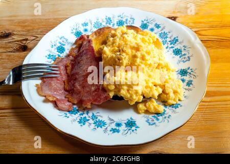 Yorkshire cafe breakfast snack with well-done bacon and scrambled egg on toasted white bloomer bread Stock Photo