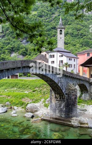 Bignasco village with San Rocco church and the ancient stone brige over the Maggia River in Valley Lavizzara, Ticino, Switzerland Stock Photo