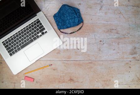 Digital e-learning laptop and mask on wood desk Stock Photo