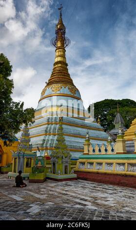 Man kneeling in prayer before the ornate gold and decorated stupa at the Shwe Sayan Pagoda, Dala, Yangon, Myanmar Stock Photo