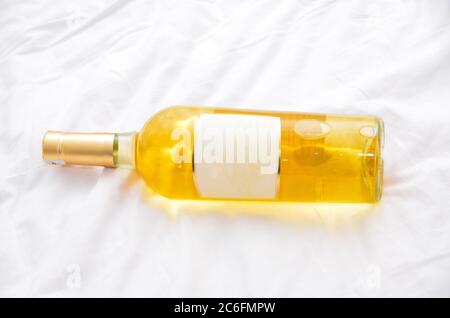 White Wine Bottle Lying on a Bed with Blank Label and Copy Space Stock Photo