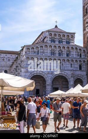 Lucca, Italy - August 17, 2019: A tourists and locals stroll on the Flea market in front of San Martino cathedral in historical centre of Lucca Stock Photo