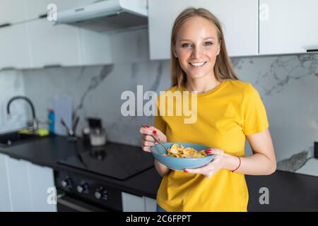 Cute young girl having cereal for breakfast at home in the kitchen Stock Photo