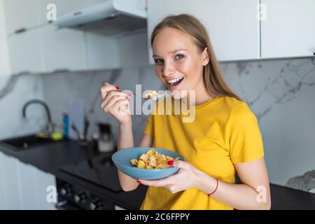 Cute young girl having cereal for breakfast at home in the kitchen Stock Photo