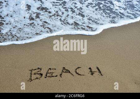 The word  'Beach' in the sand against the sea. Stock Photo