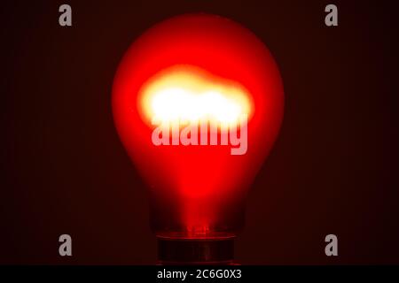 Crompton ruby red tungsten incandescent filament lightbulb lit, red bulb, lightbulb, light, lamp Stock Photo