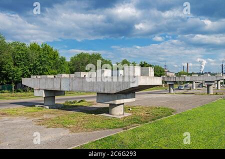 Reinforced concrete supports of an unfinished automobile viaduct against background of smoking pipes in the industrial area of city Stock Photo