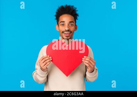 Passionate and excited african american guy in love giving his heart to soulmate, searching for other half, holding heart valentines cad and smiling Stock Photo