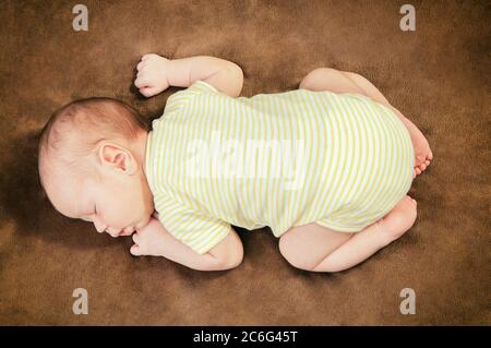 Beautiful newborn baby boy sleeping peacefully on the soft brown blanket Stock Photo