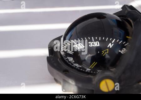 marine compass close-up with place for text. Nautical compass on yacht shows north-west direction. Gyrocompass with yellow arrow. Stock Photo
