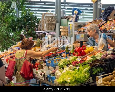 Customer paying for her Fruit and Vegetables on a stall in Mercato Albinelli, Modena, Italy. Stock Photo