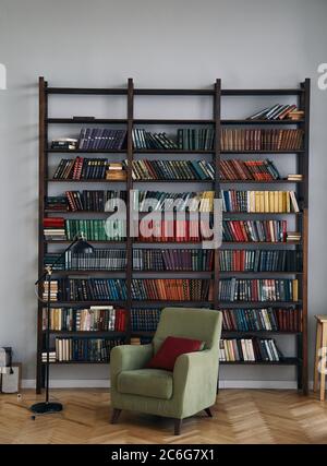 green chair in the interior. Bookcase with old books on the shelves. Books in an old wooden Cabinet Stock Photo