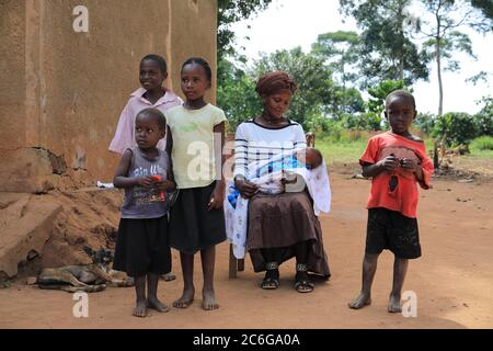 Family, woman, children, baby, sitting in front of mud hut, Uganda, East Africa Stock Photo
