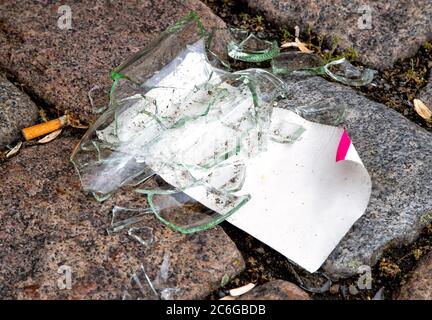 Risk of injury. Close up image of broken and shattered sharp pieces glass lying on a walkway. Stock Photo