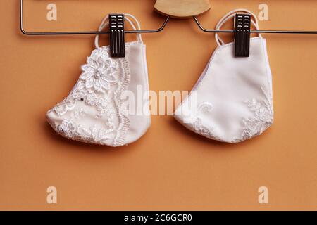 White color of lace reusable face masks hanging on clothes hanger . Sewing cloth mask to prevent the outbreak of Covid-19 virus and dust pollution . Stock Photo