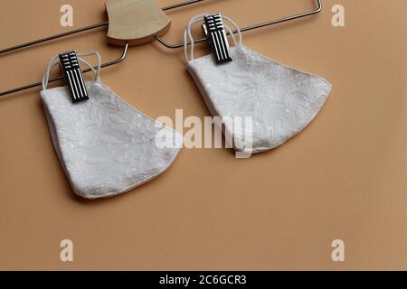 White color of lace reusable face masks hanging on clothes hanger . Sewing cloth mask to prevent the outbreak of Covid-19 virus and dust pollution . Stock Photo
