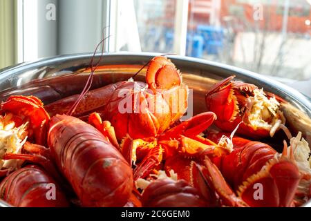A large bowl of cooked lobster sits on a table in a restaurant near a brightly lit window. Stock Photo