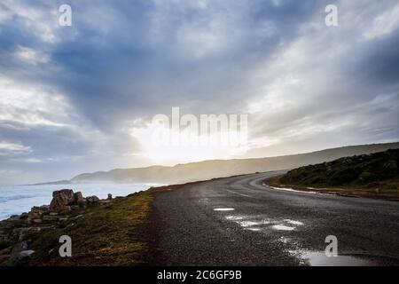 Beautiful misty sunset from a view point at Cape Point Nature Reserve, with a tar road running through the landscape, Cape Point, Cape Town, South Afr Stock Photo