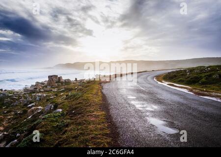 Beautiful misty sunset from a view point at Cape Point Nature Reserve, with a tar road running through the landscape, Cape Point, Cape Town, South Afr Stock Photo