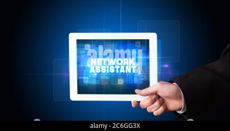 Young business person working on tablet and shows the inscription: NETWORK ASSISTANT Stock Photo