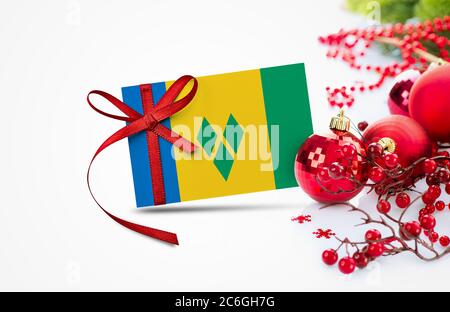 Saint Vincent And The Grenadines flag on new year invitation card with red christmas ornaments concept. National happy new year composition. Stock Photo