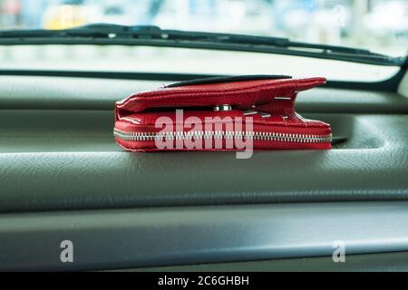Red wallet left on dashboard of car.  Stock Photo