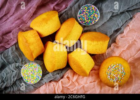 Vanilla peeled cupcakes from parchment paper with sprinkles. Top view. Stock Photo