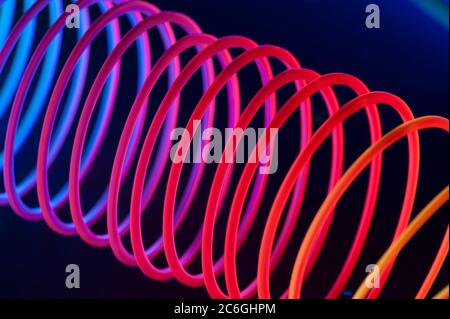 Red Circular spiral objects are viewed in close and lit with fluorescent colors against a deep blue background. Stock Photo