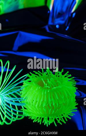 Fuzzy objects in close-up vieware lit with fluorescent colors against a deep blue background. Stock Photo