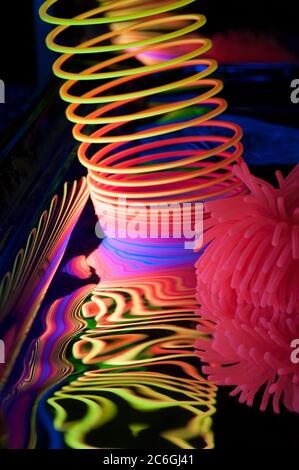 Circular and spiral objects in close-up view are lit with fluorescent colors against a deep blue background. Stock Photo