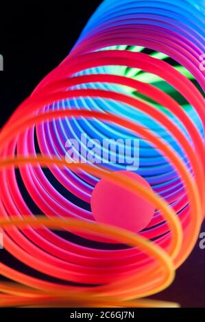 Circular spiral objects are viewed in close and lit with fluorescent colors against a deep blue background. Stock Photo