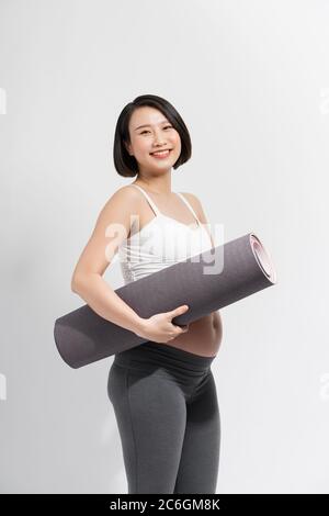 Young woman in early pregnancy with rolled mat under her arm going to prenatal yoga class Stock Photo