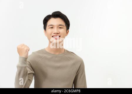 Happy excited Asian man raising his arm up to celebrate success Stock Photo