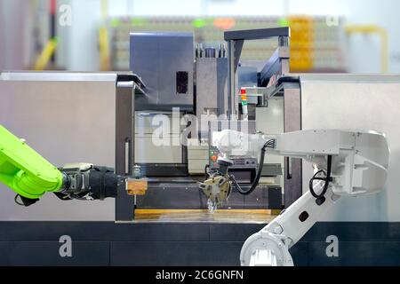 Industrial robotics teamwork on working with CNC lathe machine in smart factory on blurred background, industry 4.0 and technology concept Stock Photo