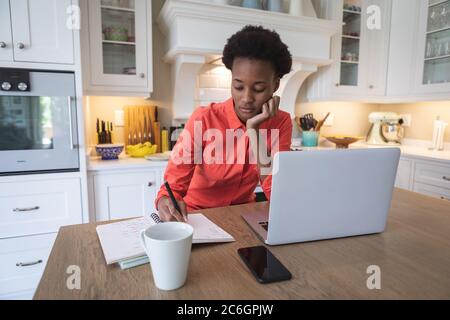 Woman taking notes while working in the kitchen Stock Photo