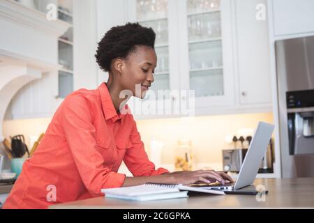 Woman using laptop in the kitchen Stock Photo