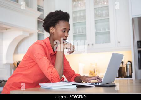 Woman using laptop in the kitchen Stock Photo