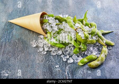 Frozen Edamame or soybeans in the mix with crushed ice on a blue background. Stock Photo