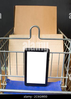 shopping cart with cardboard boxes. Close-up with a tablet lying in it. Delivery to the consumer, Online trade. On black background Stock Photo