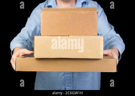 Man in blue shirt holds three cardboard boxes. delivery of goods from online stores. Stock Photo