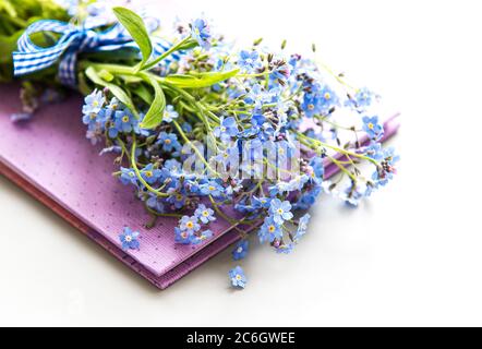 Forget me not flowers and notebook on white background Stock Photo